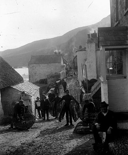 Fishermen carrying crab pots along the street at Hallsands. 'Prettyjohn' house on right.