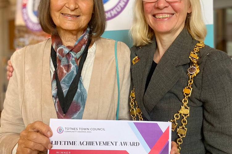 Cllr Emily Price with Sue Holmes, who received the Totnes Town Council Lifetime Achievement Community Award in 2024. Sue was nominated for an individual community award for her central role at Leechwell Garden Association. 
In recognition of the exceptional length of service and her dedication, Town Councillors chose to give Sue a very special Lifetime Achievement Award.